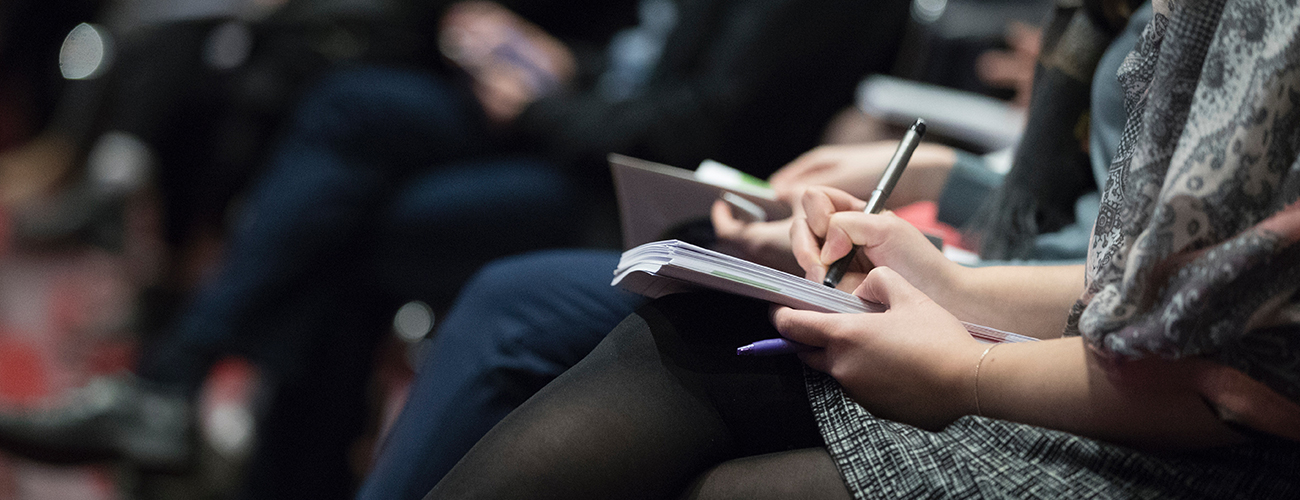 Woman writing notes during conference